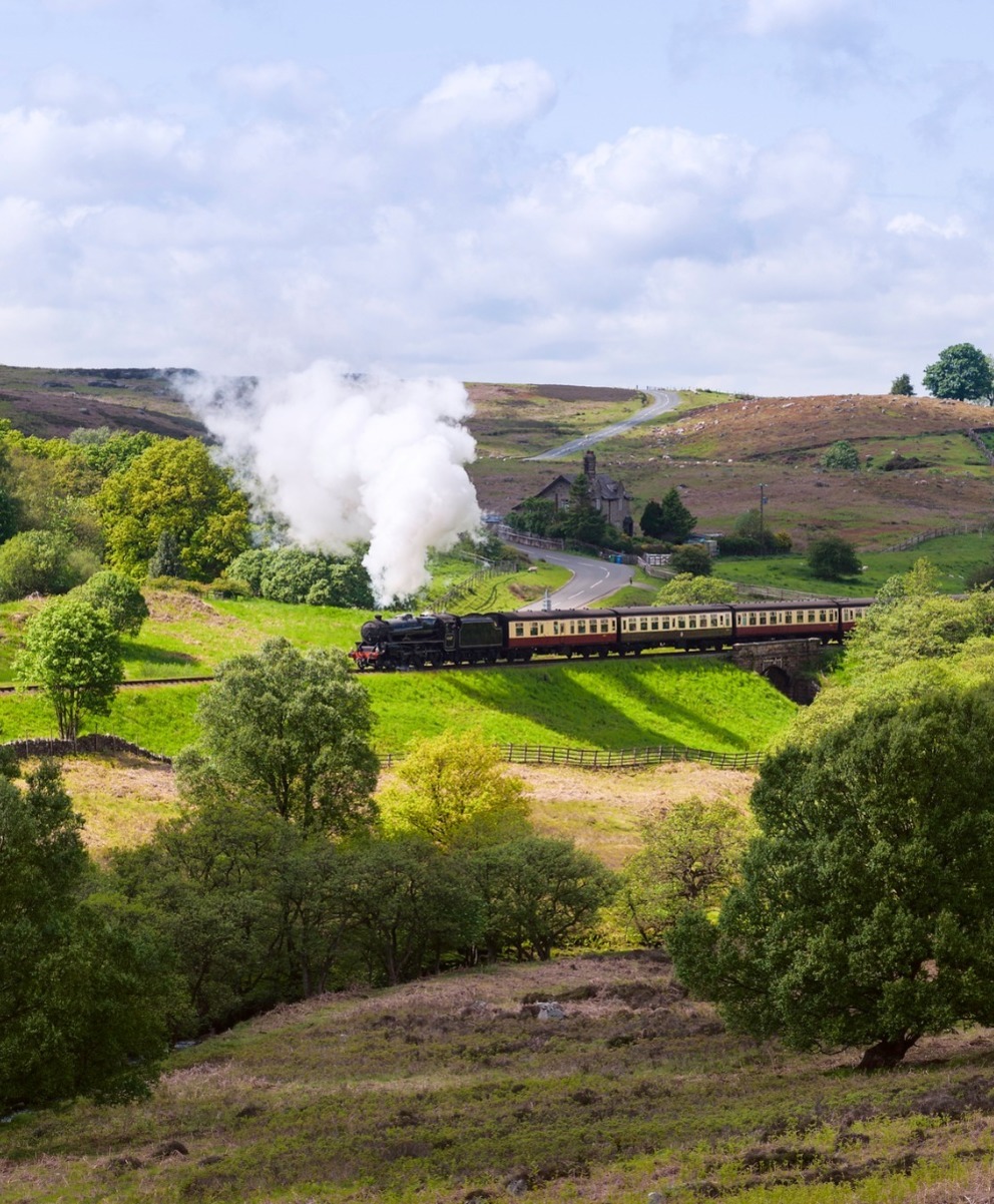 Train running along with the track with green hills and landscape
