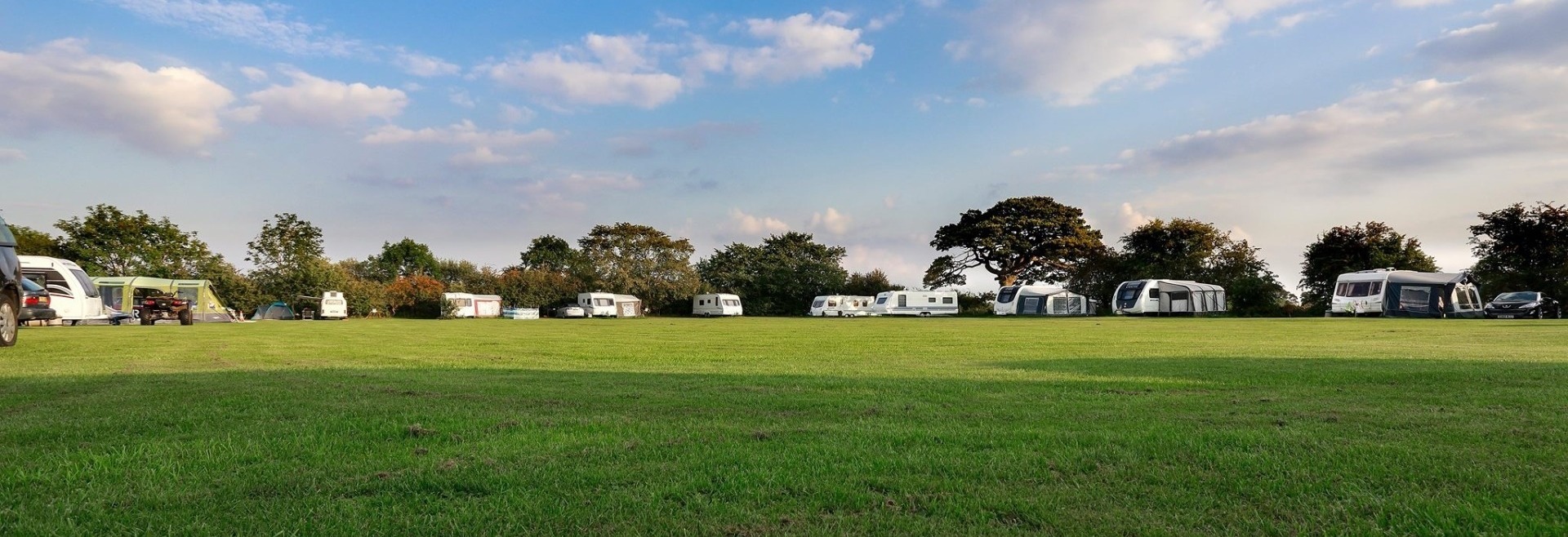 Westgate Farm Caravan Pitches with green grass and blue sky with fluffy white clouds